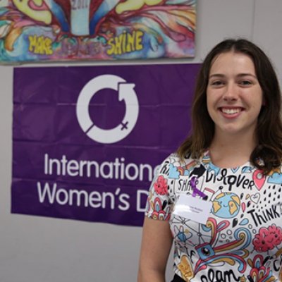 Woman standing in front of a purple sign.